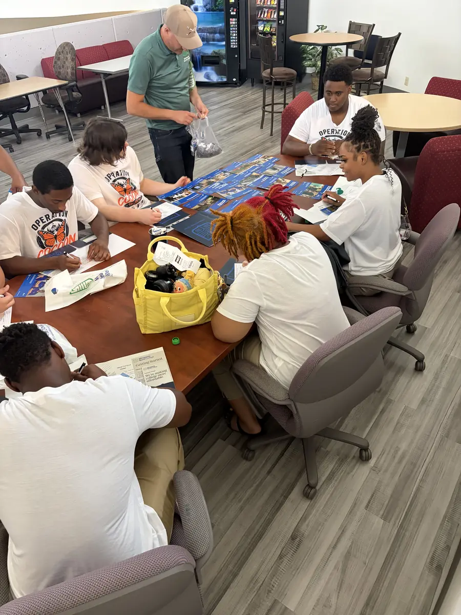 Students seated around a table during a planning activity on the college tour.